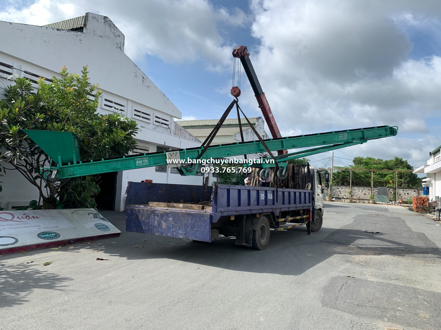 van chuyen băng tải lồng máng nâng hạ di động đến nơi bàn giao